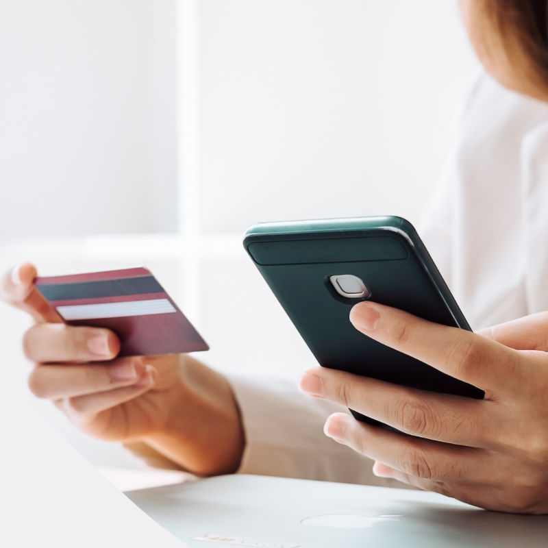 Person hält in einer Hand ein Handy und in der anderen Hand eine EC-Karte